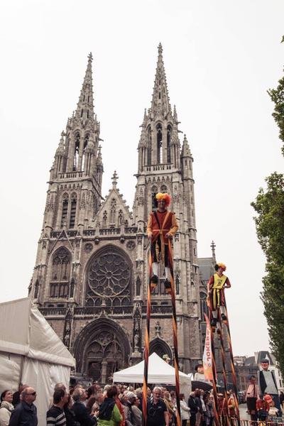 Steltenlopers op hoge stelten voor een gotische kerk