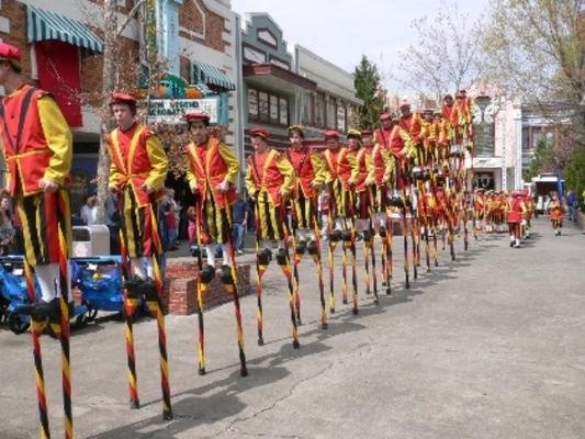 Lange rij steltenlopers in een straat met publiek