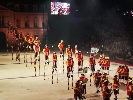 Optreden van de steltenlopers en de fanfare in een verlichte arena