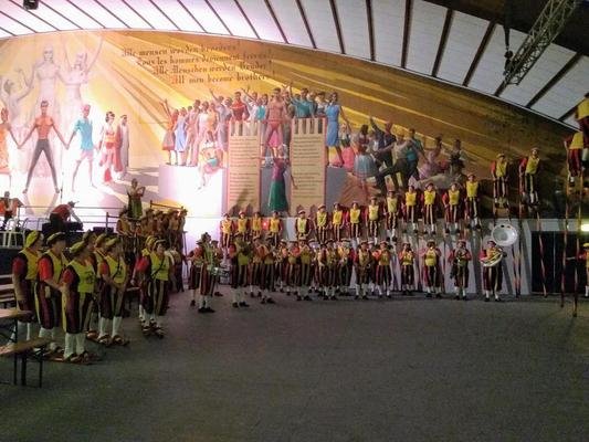 De groep in kostuum opgesteld in een grote feesttent