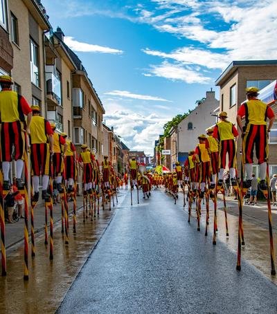 Steltenlopers in een lange stoet door een natte straat