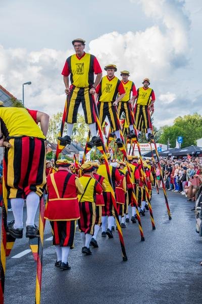 Steltenlopers boven de stoet en het publiek
