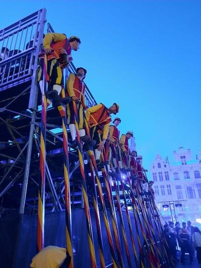 Steltenlopers op een stellage met de gevels van de Grote Markt erachter