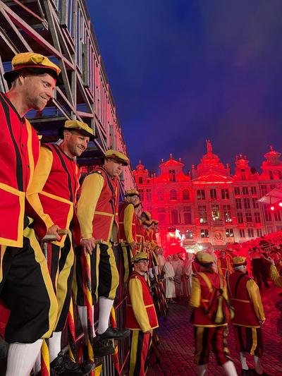 Steltenlopers op een rij langs de tribune bij rood verlichte gevels