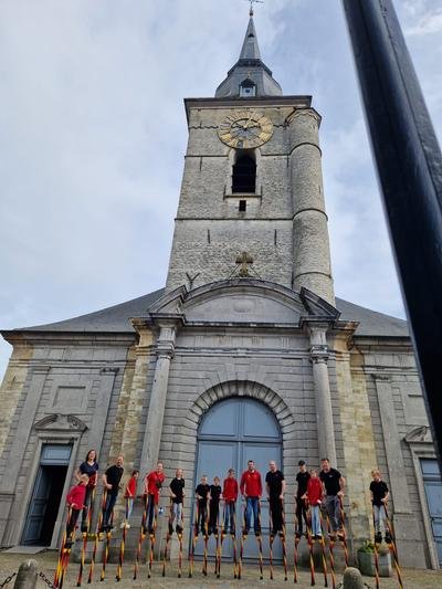 Groepsfoto van de trainingsgroep op stelten voor de kerk