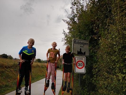 Drie kinderen op stelten aan het bord van Kobbegem