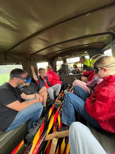 Deelnemers met blinddoek achterin een legerjeep