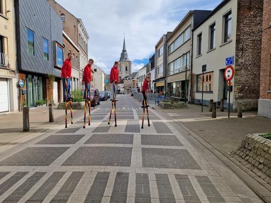 Vier steltenlopers in trainingskledij in een winkelstraat