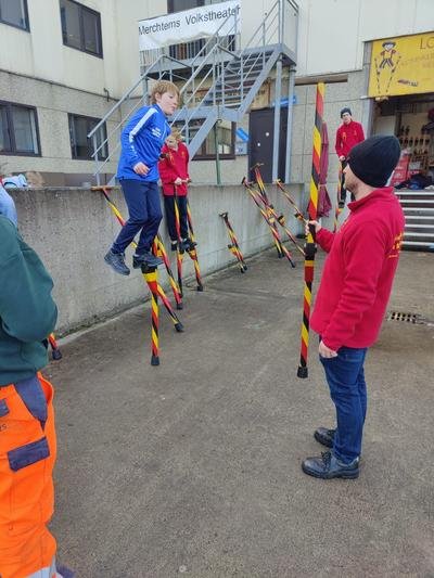 Kinderen oefenen op stelten onder begeleiding van een trainer