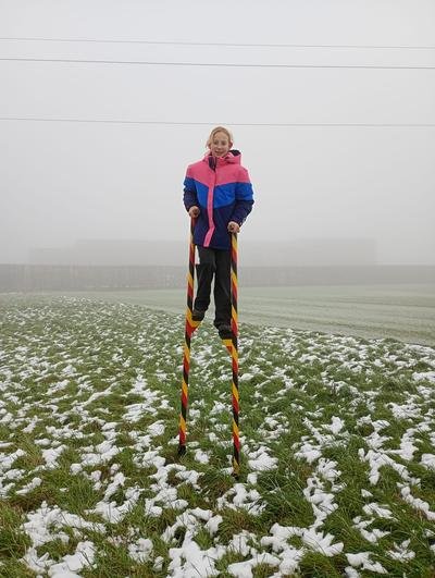 Meisje op stelten in een besneeuwd veld