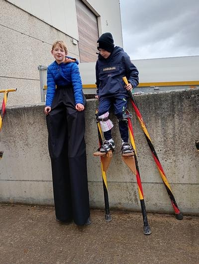 Twee kinderen stappen op stelten van op de muur