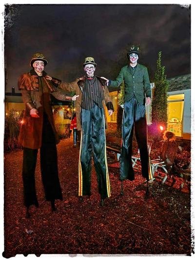 Drie steltenlopers in steampunkkostuum bij avond