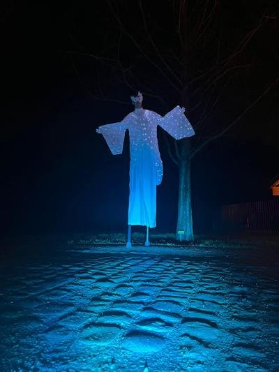 Steltenloper in wit lichtgevend kostuum in blauw licht