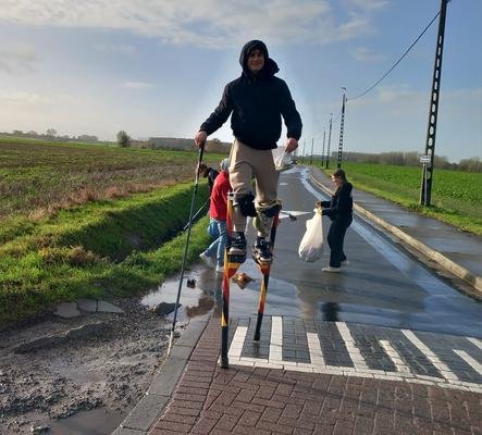Steltenloper in een trui met kap op een landweg