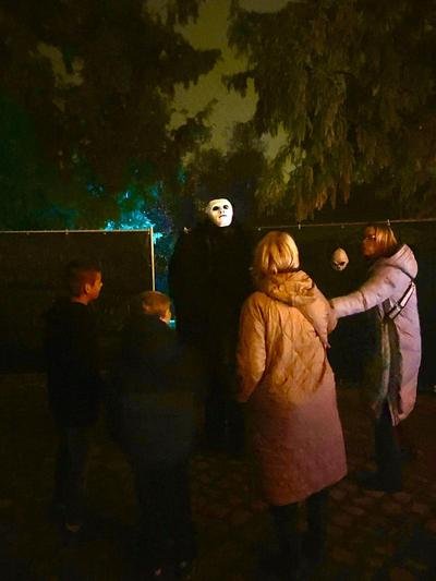 Gemaskerde steltenloper tussen bezoekers in het donker